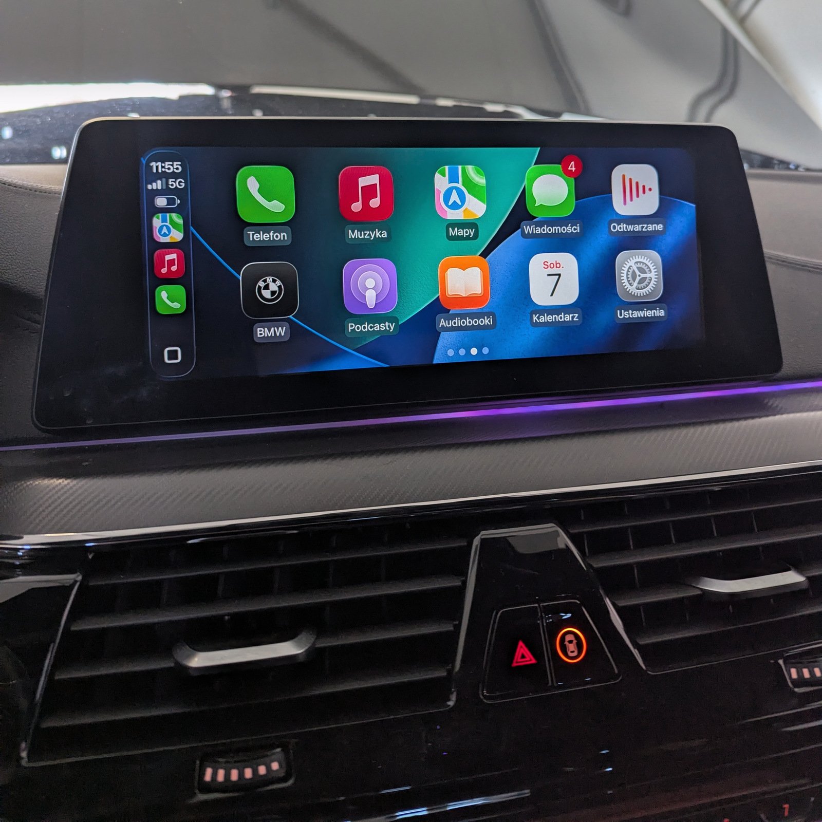 BMW multimedia display showing Apple CarPlay in Polish with purple interior ambient lighting.