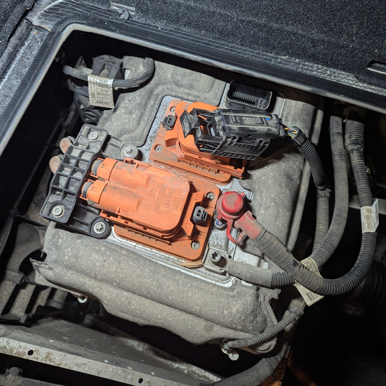 BMW i3 EME control unit with orange high-voltage connectors and wiring beneath the luggage compartment floor.