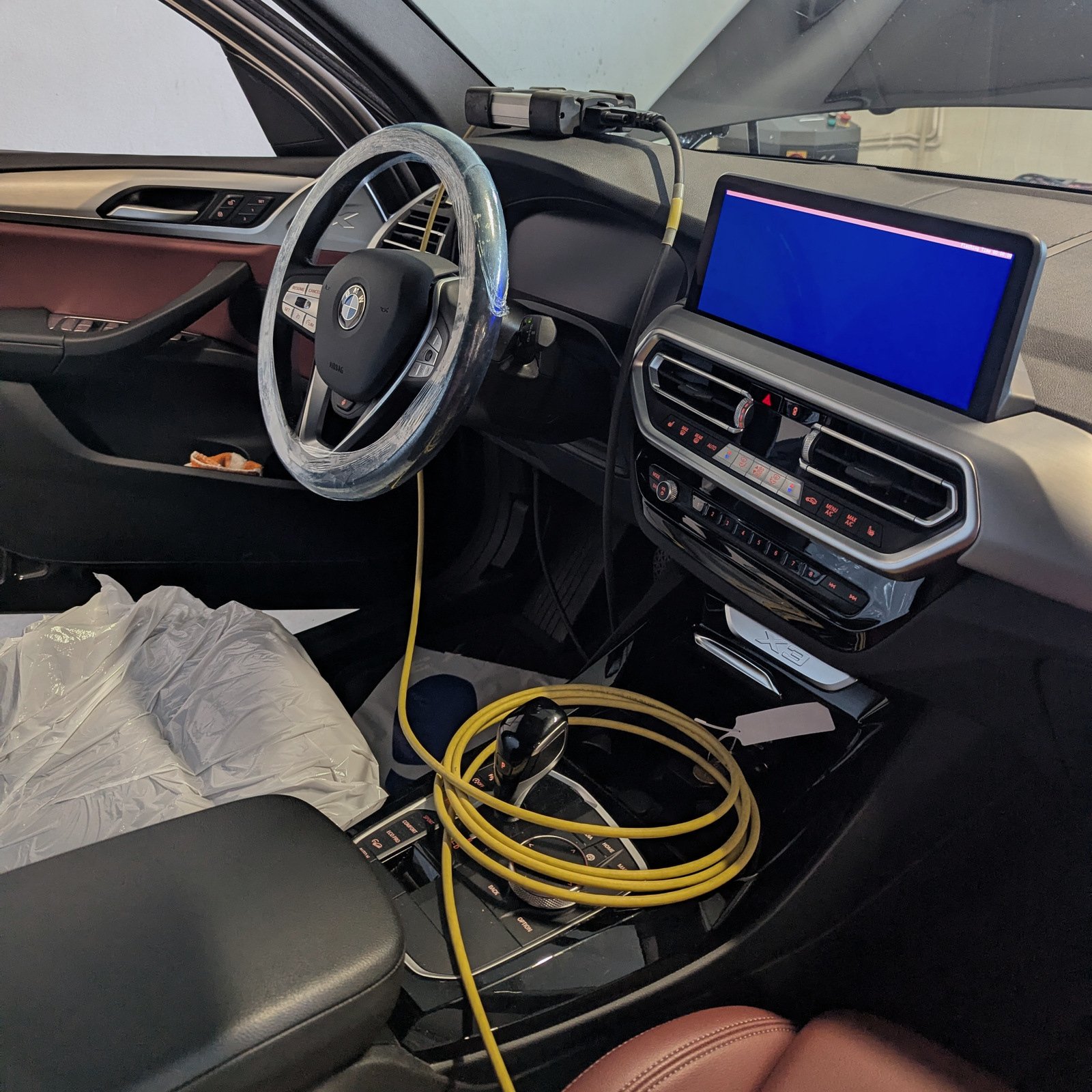 BMW interior with a connected interface, yellow cable and blue service screen.
